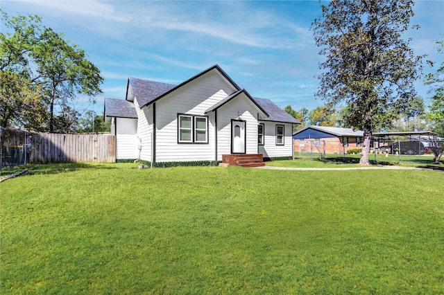 view of front of home featuring fence, a front yard, and a shingled roof