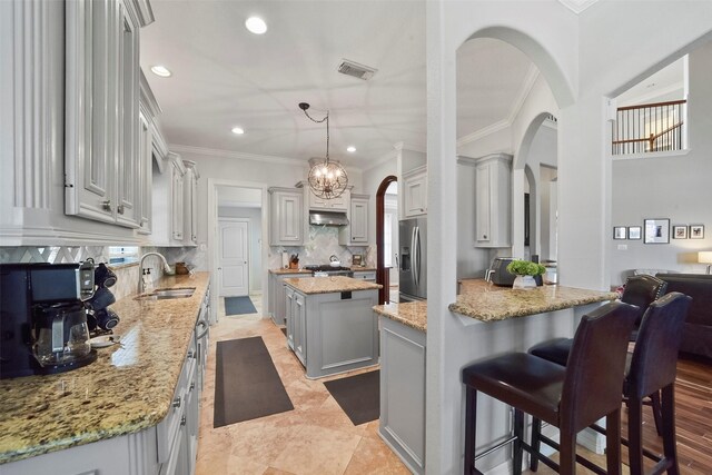 27603 Siandra Creek Ln, Spring, TX 77386 - kitchen with arched walkways, gray cabinets, under cabinet range hood, stainless steel fridge with ice dispenser, and a sink