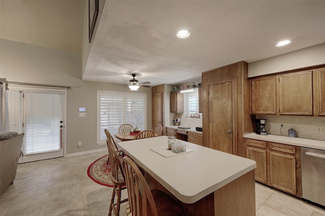 900 Manchester Dr, Conroe, TX 77304 - kitchen with dishwasher, brown cabinetry, light countertops, a breakfast bar area, and a center island