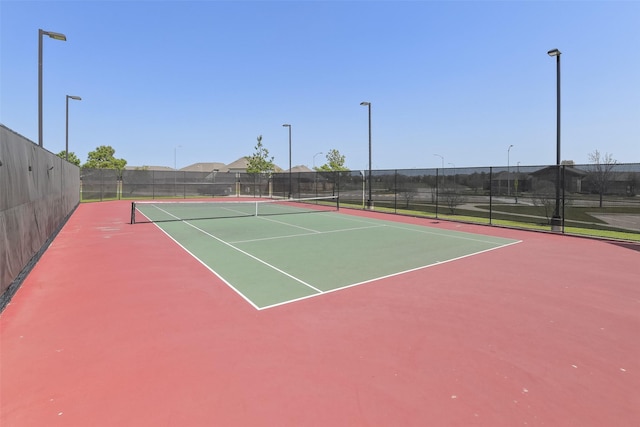view of tennis court with community basketball court and fence