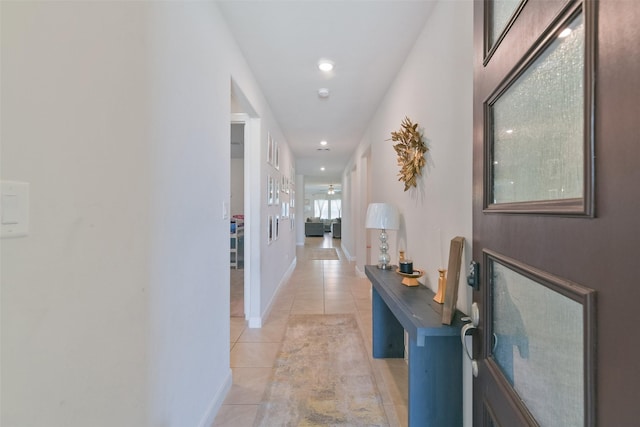 hall featuring baseboards, recessed lighting, and light tile patterned floors