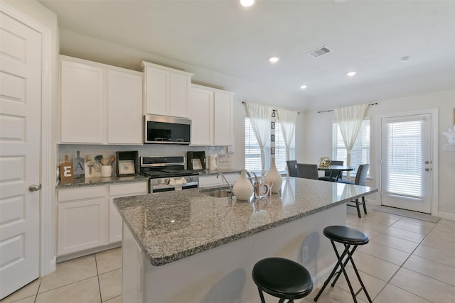 kitchen featuring light tile patterned floors, stainless steel appliances, decorative backsplash, a sink, and visible vents