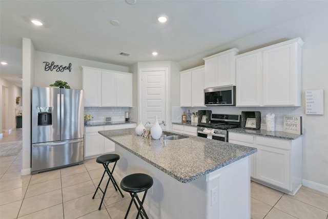 kitchen featuring visible vents, stainless steel appliances, an island with sink, a sink, and light tile patterned floors