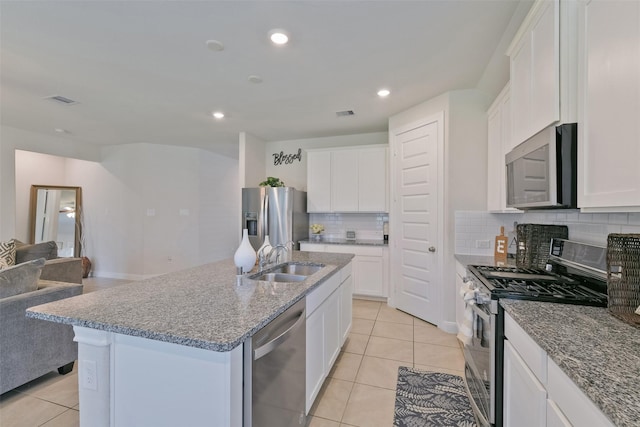 kitchen featuring light tile patterned flooring, open floor plan, a sink, and stainless steel appliances