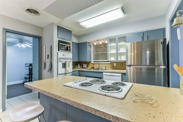 kitchen featuring light countertops, stainless steel appliances, blue cabinets, a sink, and visible vents