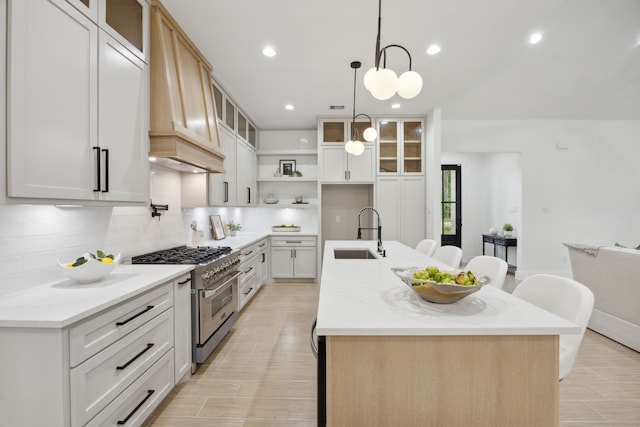 1252 Rd 6604, Dayton, TX 77535 - kitchen featuring a sink, stainless steel range, custom exhaust hood, a center island with sink, and backsplash