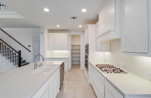 693 Cape Capri Dr, Katy, TX 77493 - kitchen with tasteful backsplash, a sink, visible vents, white cabinets, and appliances with stainless steel finishes