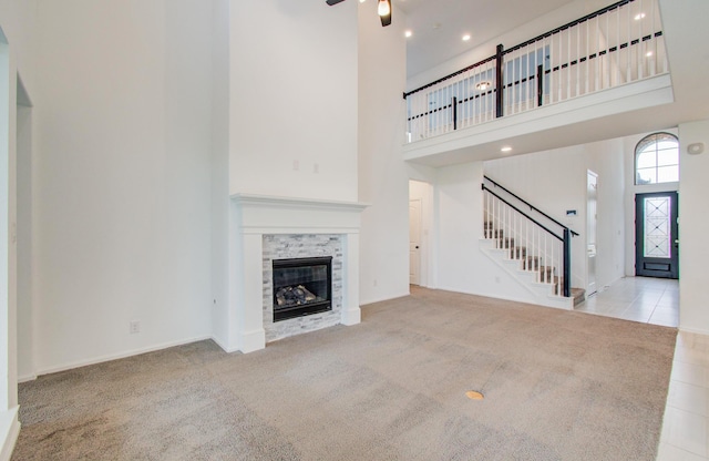 693 Cape Capri Dr, Katy, TX 77493 - unfurnished living room featuring stairs, a high ceiling, a tiled fireplace, and carpet flooring