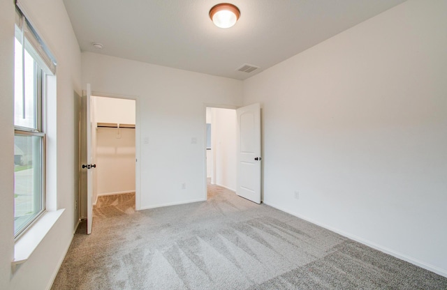 693 Cape Capri Dr, Katy, TX 77493 - unfurnished bedroom featuring baseboards, a walk in closet, multiple windows, and light carpet