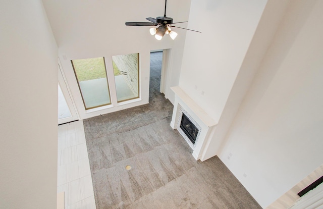 693 Cape Capri Dr, Katy, TX 77493 - unfurnished living room featuring a towering ceiling, carpet floors, a glass covered fireplace, and a ceiling fan