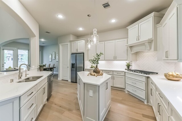 17429 Orchid Falls Ln, Conroe, TX 77302 - kitchen featuring appliances with stainless steel finishes, a center island, a sink, decorative backsplash, and light countertops