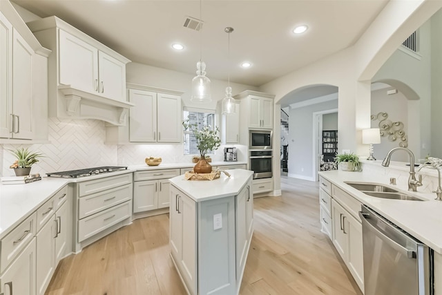 17429 Orchid Falls Ln, Conroe, TX 77302 - kitchen featuring a sink, stainless steel appliances, light countertops, tasteful backsplash, and arched walkways