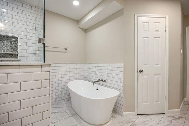 11814 Drexelbrook Dr, Houston, TX 77077 - bathroom with marble finish floors, a freestanding bath, tile walls, recessed lighting, and a wainscoted wall