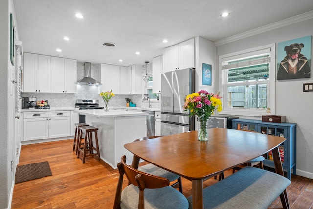dining room with ornamental molding, light wood finished floors, recessed lighting, and visible vents