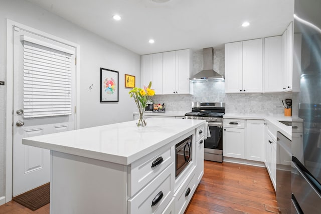 kitchen featuring light countertops, appliances with stainless steel finishes, backsplash, and wall chimney range hood