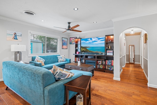 living area featuring ceiling fan, crown molding, arched walkways, recessed lighting, and light wood-style flooring