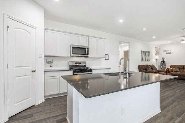 4984 Pismo Ray Dr, Katy, TX 77493 - kitchen featuring dark countertops, appliances with stainless steel finishes, an island with sink, a sink, and dark wood-style floors
