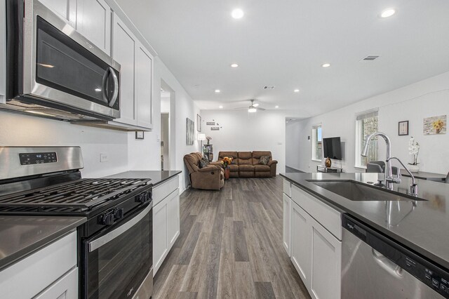 4984 Pismo Ray Dr, Katy, TX 77493 - kitchen with stainless steel appliances, a sink, dark countertops, visible vents, and wood finished floors