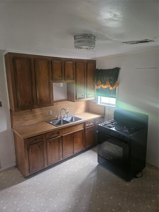112 N Parrish St, Angleton, TX 77515 - kitchen with a sink, black range with gas cooktop, tasteful backsplash, light countertops, and dark brown cabinets