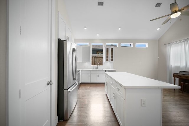 kitchen with freestanding refrigerator, wood finished floors, a sink, a center island, and recessed lighting