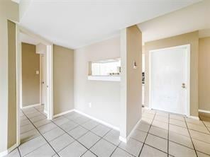 empty room with baseboards and light tile patterned floors