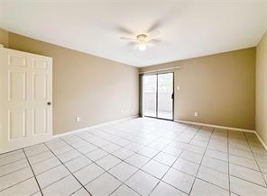 empty room with light tile patterned flooring, ceiling fan, and baseboards