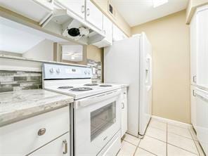 kitchen with light tile patterned floors, electric range, visible vents, white cabinets, and light stone countertops