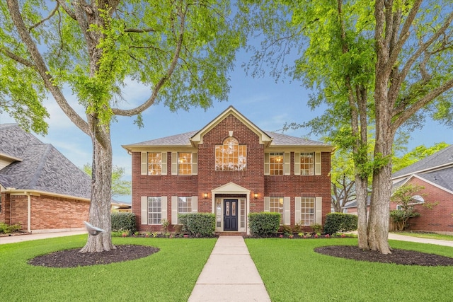 colonial-style house featuring brick siding and a front lawn