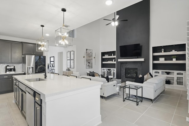 21134 Coral View Dr, Cypress, TX 77433 - kitchen with a sink, a glass covered fireplace, a ceiling fan, a high ceiling, and light tile patterned floors