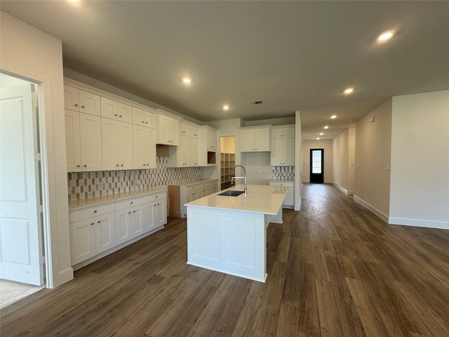 31319 Hastings Creek Ln, Fulshear, TX 77441 - kitchen featuring dark wood finished floors, white cabinetry, tasteful backsplash, a center island with sink, and recessed lighting