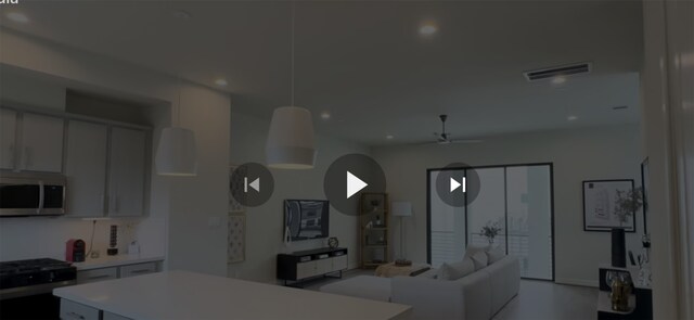 kitchen featuring visible vents, range with gas cooktop, a ceiling fan, open floor plan, and white microwave