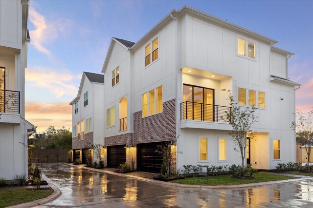 view of front of house with driveway, an attached garage, board and batten siding, and a balcony