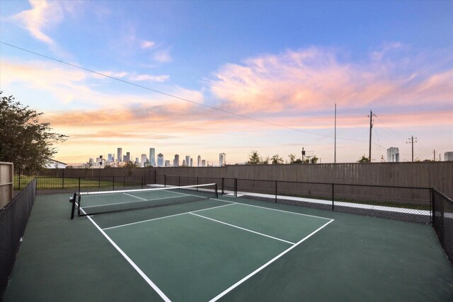 view of tennis court with a city view, fence, and community basketball court