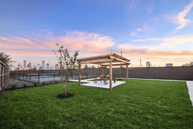 yard at dusk with a pergola, a view of city, fence, and a patio