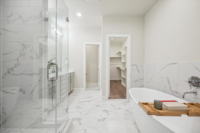bathroom with marble finish floor, a marble finish shower, a freestanding tub, recessed lighting, and a spacious closet