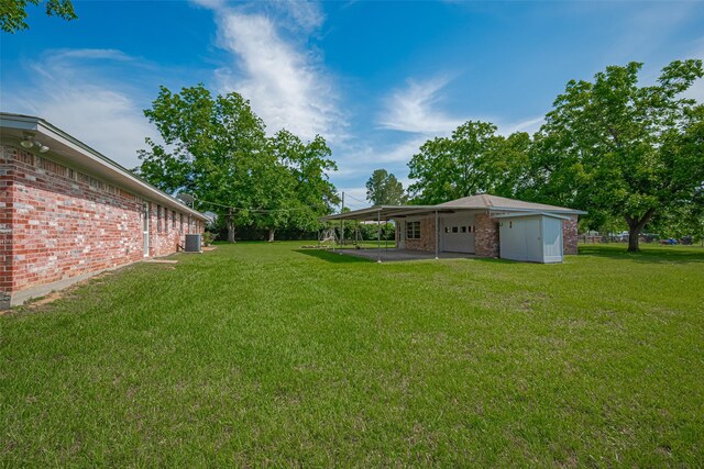 26003 Fountaine Bleau Dr, Tomball, TX 77377 - view of green lawn featuring a carport, a garage, and central air condition unit