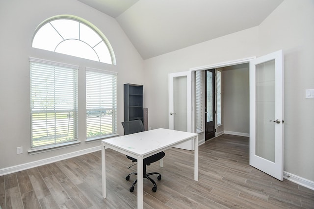 home office with lofted ceiling, plenty of natural light, french doors, and wood finished floors