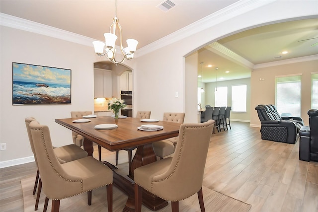 dining room with arched walkways, visible vents, baseboards, and light wood-style flooring