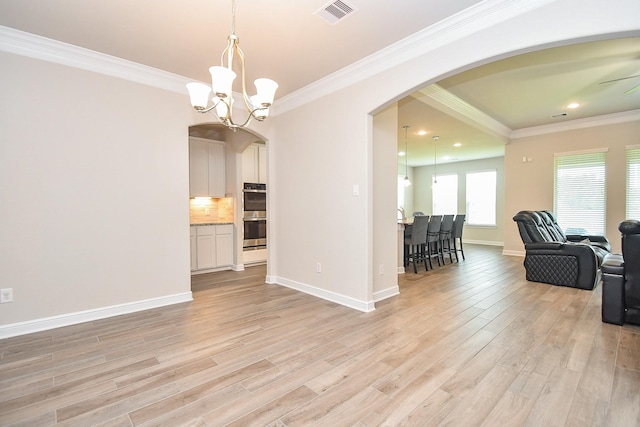 living area featuring arched walkways, light wood finished floors, visible vents, and ornamental molding