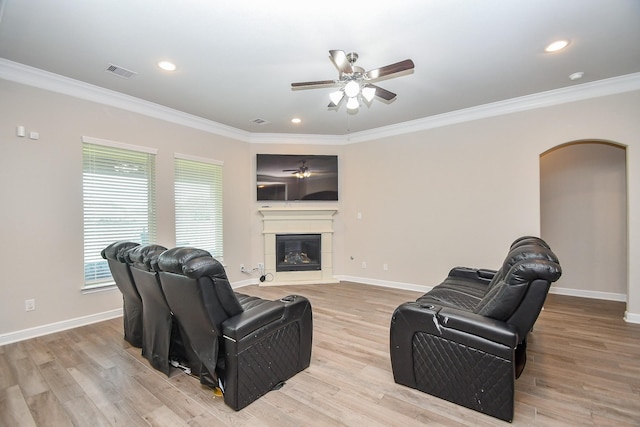 living room with baseboards, crown molding, visible vents, ceiling fan, and arched walkways