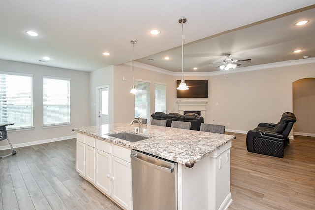 kitchen featuring stainless steel dishwasher, a sink, light wood-type flooring, open floor plan, and baseboards