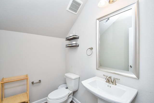 half bathroom with a sink, toilet, vaulted ceiling, baseboards, and visible vents