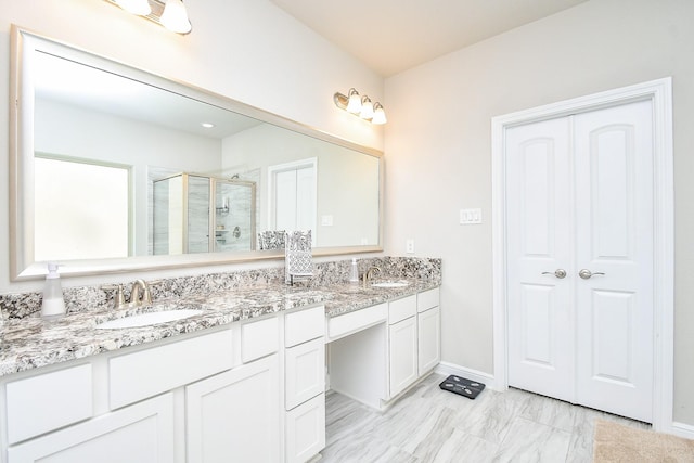 full bath with a stall shower, double vanity, a sink, and baseboards