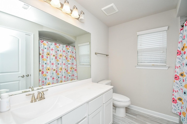 bathroom featuring toilet, baseboards, visible vents, wood finished floors, and vanity