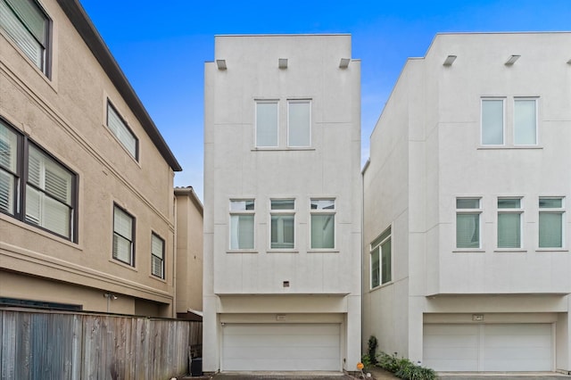 exterior space with a garage, driveway, stucco siding, and fence