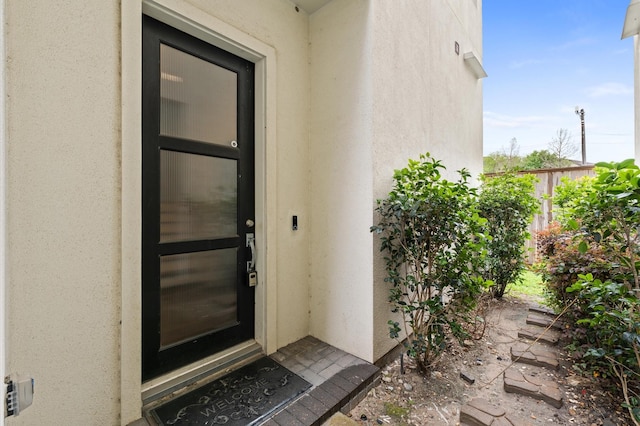 entrance to property with stucco siding and fence