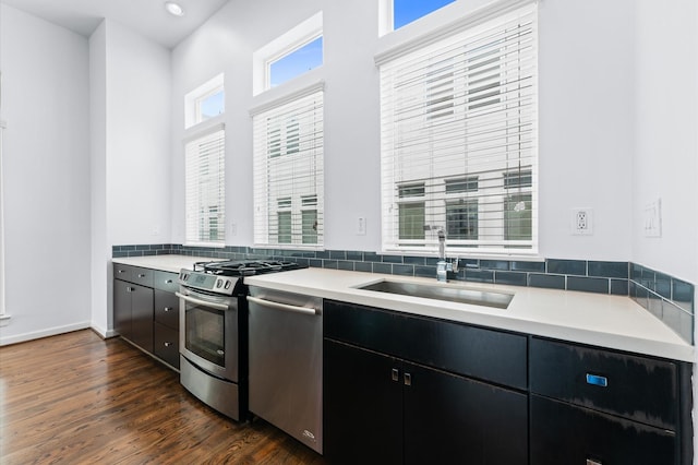 kitchen featuring light countertops, dark wood finished floors, appliances with stainless steel finishes, a sink, and dark cabinetry