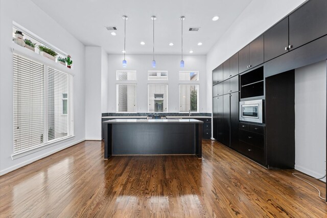 kitchen featuring visible vents, stainless steel microwave, recessed lighting, dark wood-style floors, and a center island