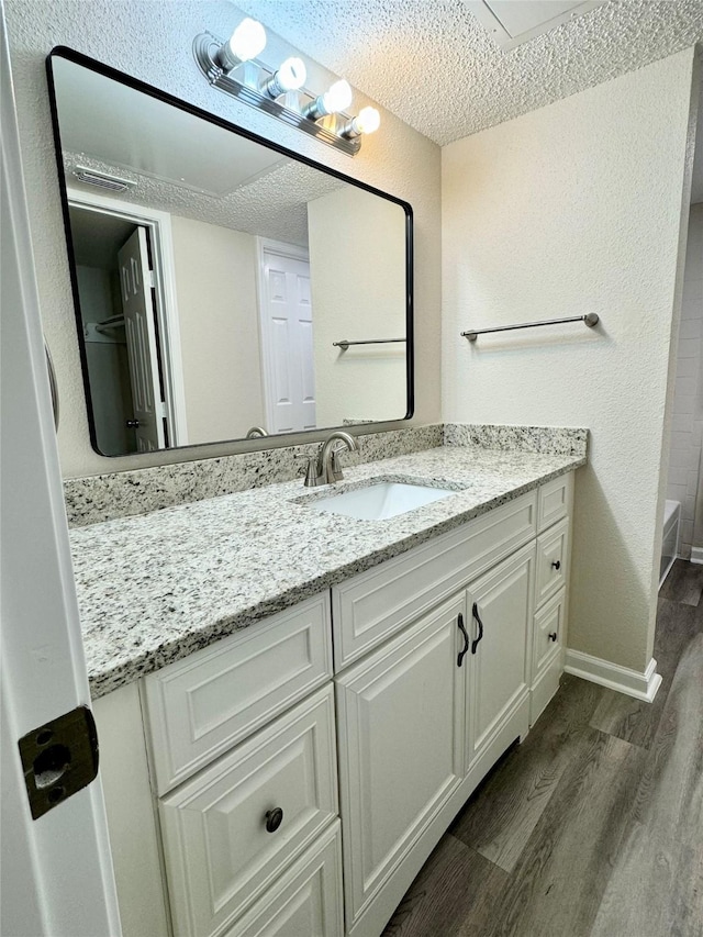 2750 Holly Hall St Unit 1301, Houston, TX 77054 - bathroom with wood finished floors, vanity, a textured ceiling, baseboards, and a tub