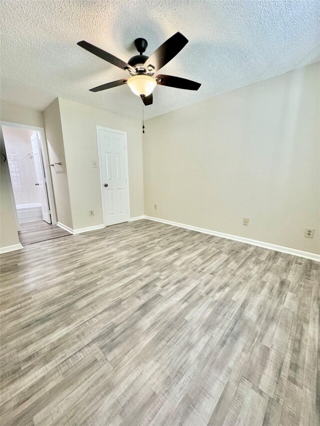 2750 Holly Hall St Unit 1301, Houston, TX 77054 - empty room featuring light wood-style flooring, ceiling fan, baseboards, and a textured ceiling